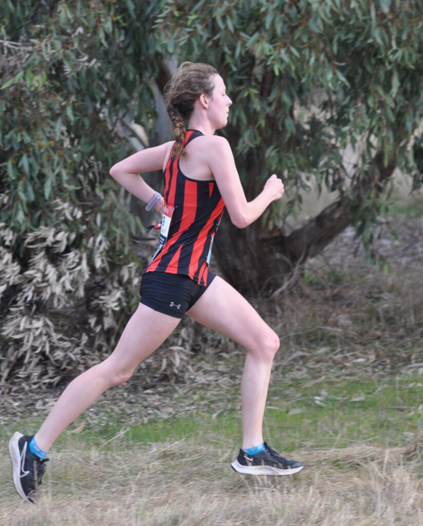 A female runner strides powerfully along a dirt path