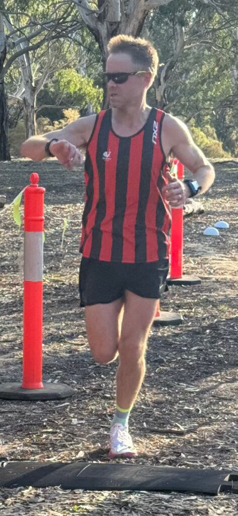 A runner crosses a finish mat looking at his watch